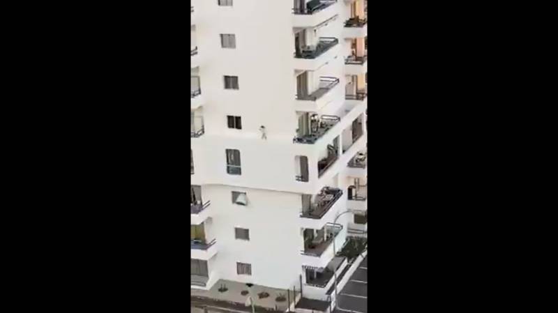 Niña corre en cornisa en cuarto piso de un edificio